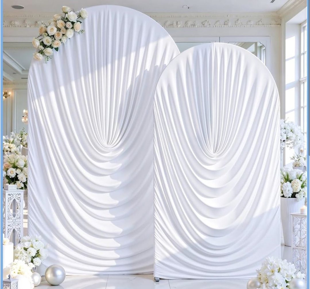 White draped arch backdrops in a bright ballroom with white florals